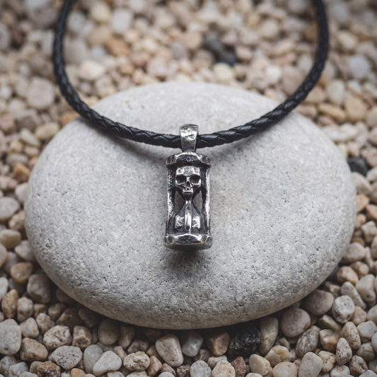Eight Bells necklace in .999 fine silver — an hourglass with a skull in the upper chamber, open through the center, on a black braided leather cord