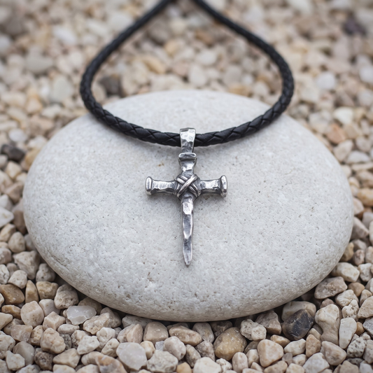 Three Nails necklace in .999 fine silver — three hammered nails bound with wire at the crossing, heads left rough, on a black braided leather cord